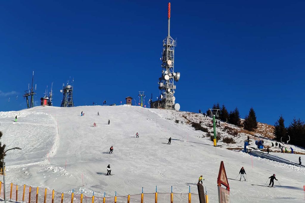 Mottarone with snow and several people skiing on a sunny day